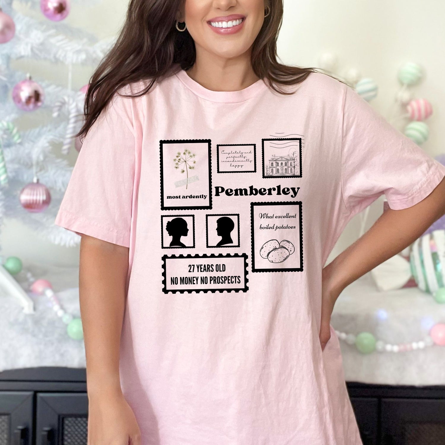 A woman wearing a pink tshirt that has a collection of stamps from Pemberley on them.