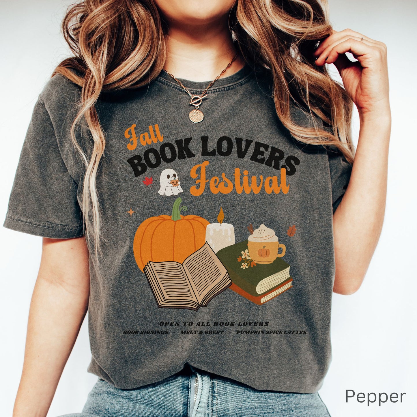 Woman wearing a Pepper Black Comfort Colors Tshirt with 'Fall Book Lovers Festival' design featuring a pumpkin, books, and a ghost for a fictional Book Lovers Festival. Starlit Prose Bookish Merch Australia