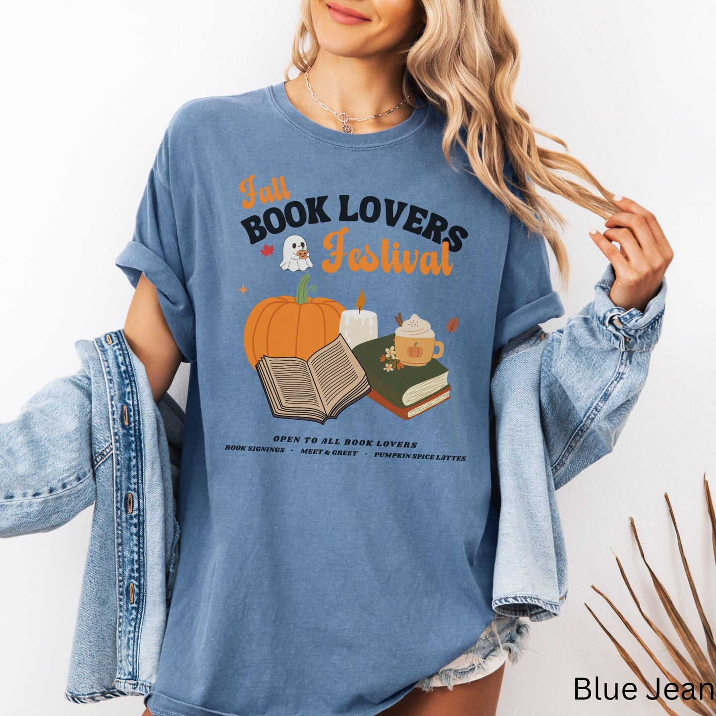Woman wearing a Blue Jean Comfort Colors Tshirt with 'Fall Book Lovers Festival' design featuring a pumpkin, books, and a ghost for a fictional Book Lovers Festival. Starlit Prose Bookish Merch Australia