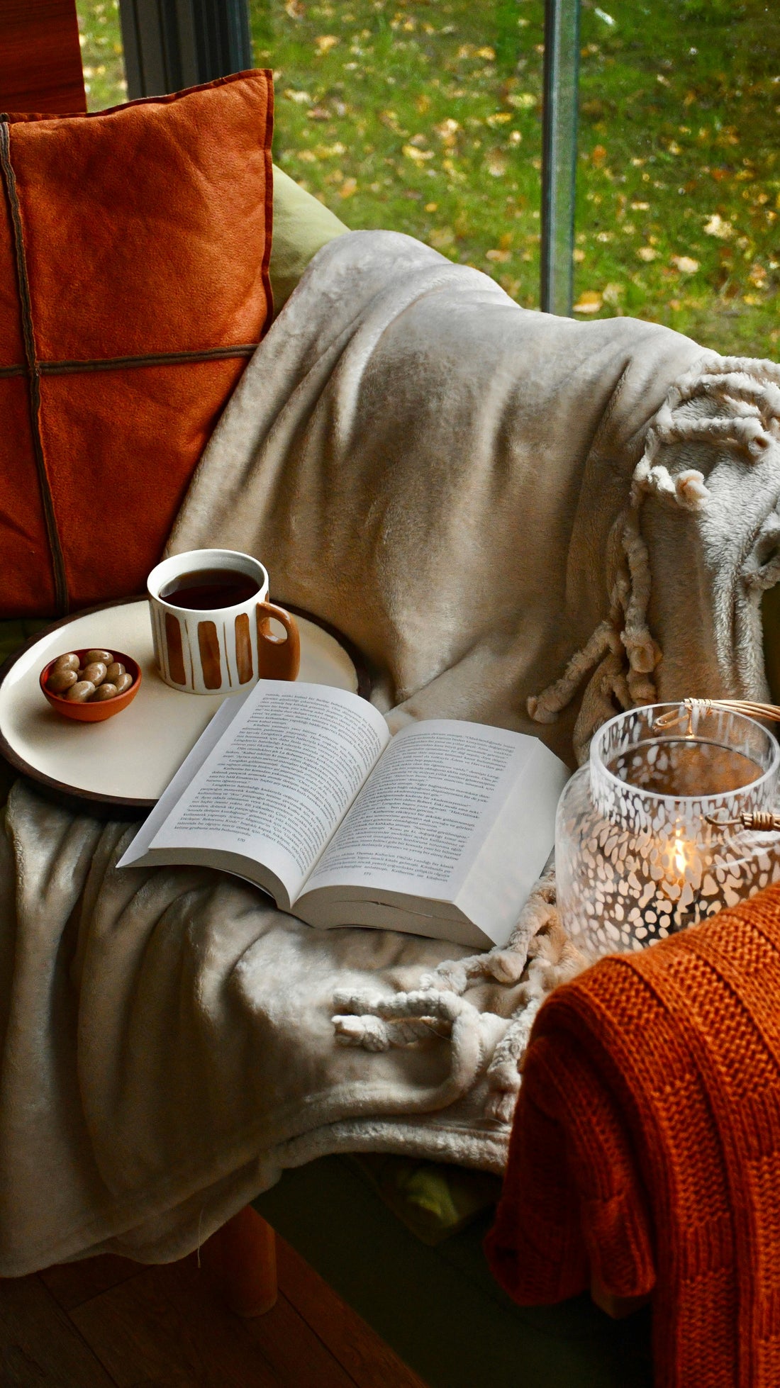 Cozy reading nook with coffee, book, candle and throw blanket