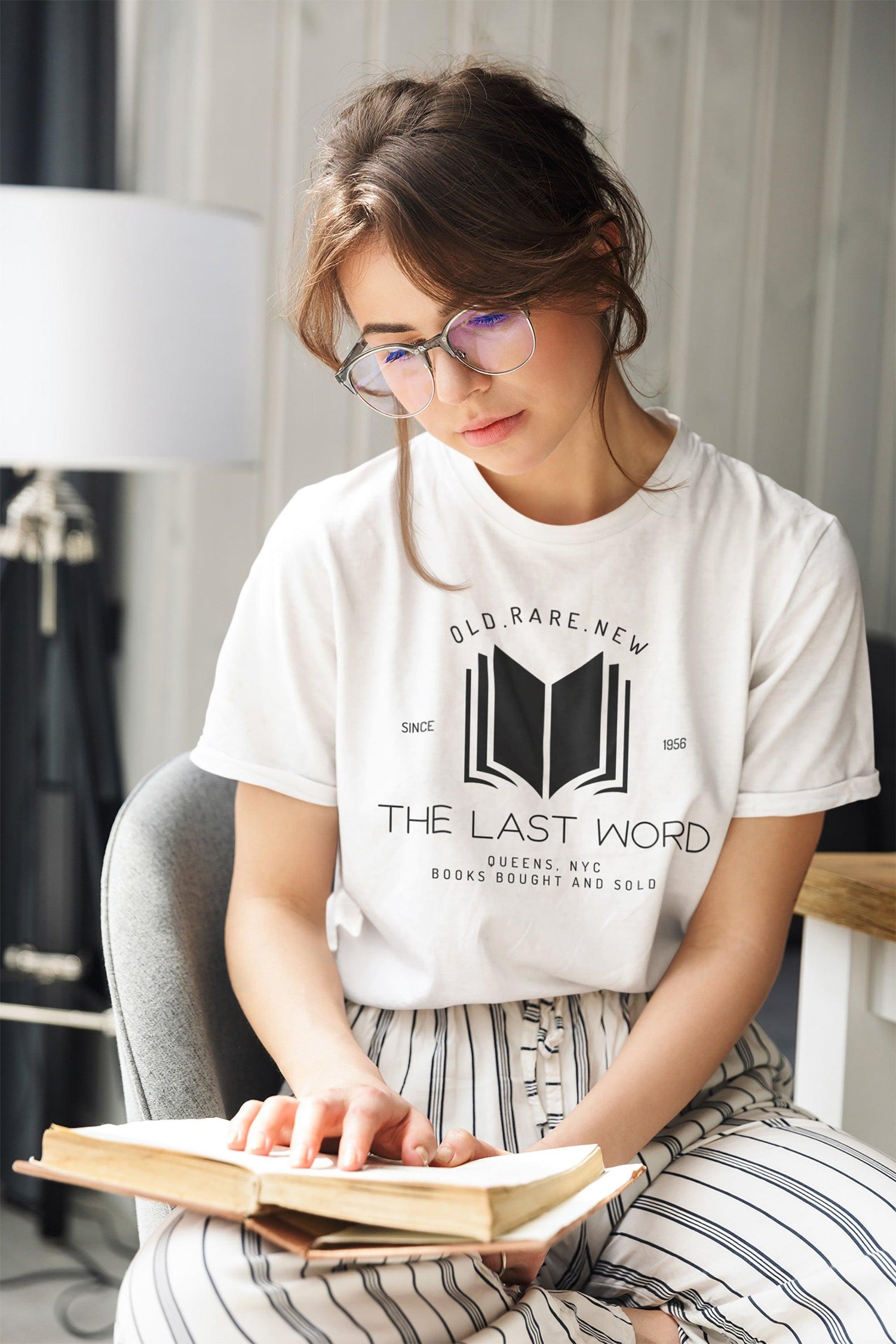Woman wearing a white tshirt that shows The Last Word book store with a graphic of abook. This collection is for fans of Victoria Schwab. Starlit Prose bookish merch