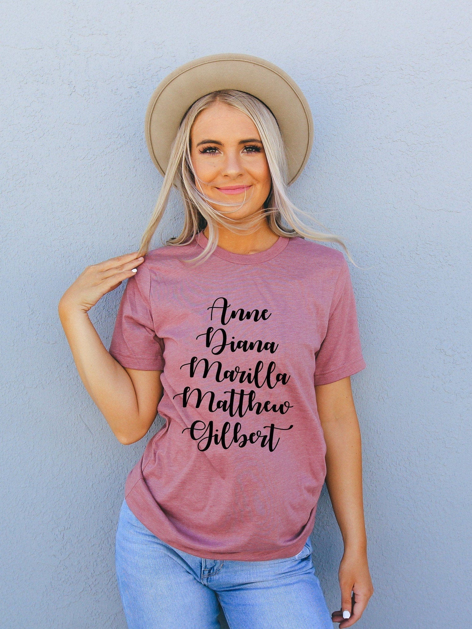 Woman wearing a Heather Mauve colour shirt, with the names of the characters from Anne of Green Gables.