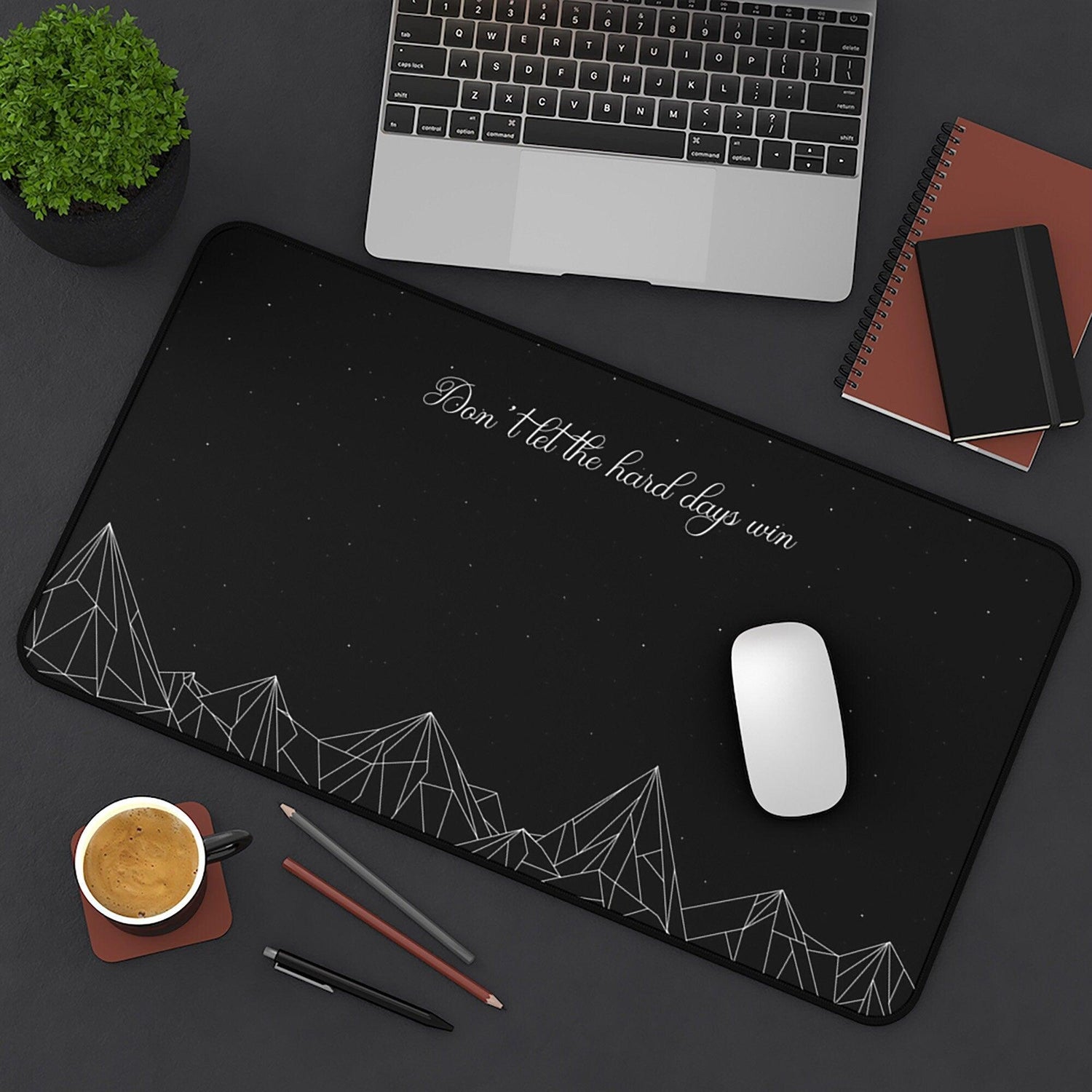 A desk mat with mountains and a quote that says "don't let the hard days win" from ACOTAR.