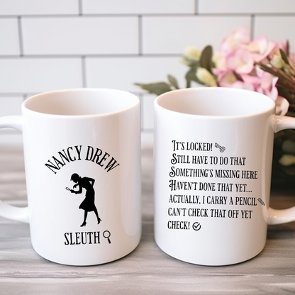 Two white mugs with text and graphics relating to Nancy Drew on a wooden surface with a blurred background