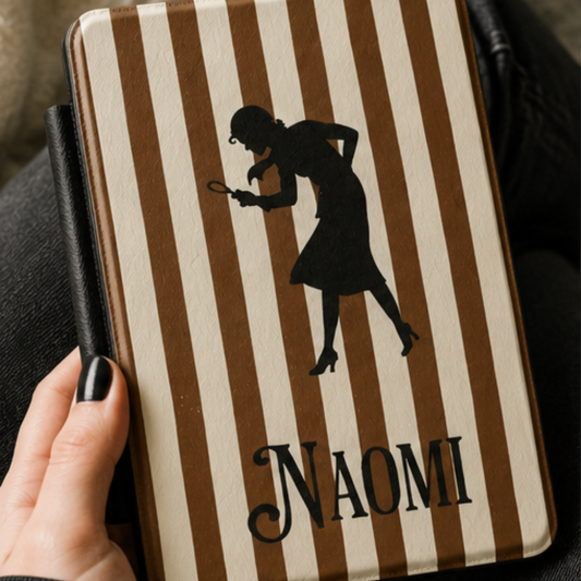 A close-up of a Personalised Nancy Drew Kindle Case, featuring a brown and cream vertical stripe pattern with a black silhouette of Nancy Drew holding a magnifying glass and a custom name in vintage style typography at the bottom. Designed by Starlit Prose Bookish Merch Australia.