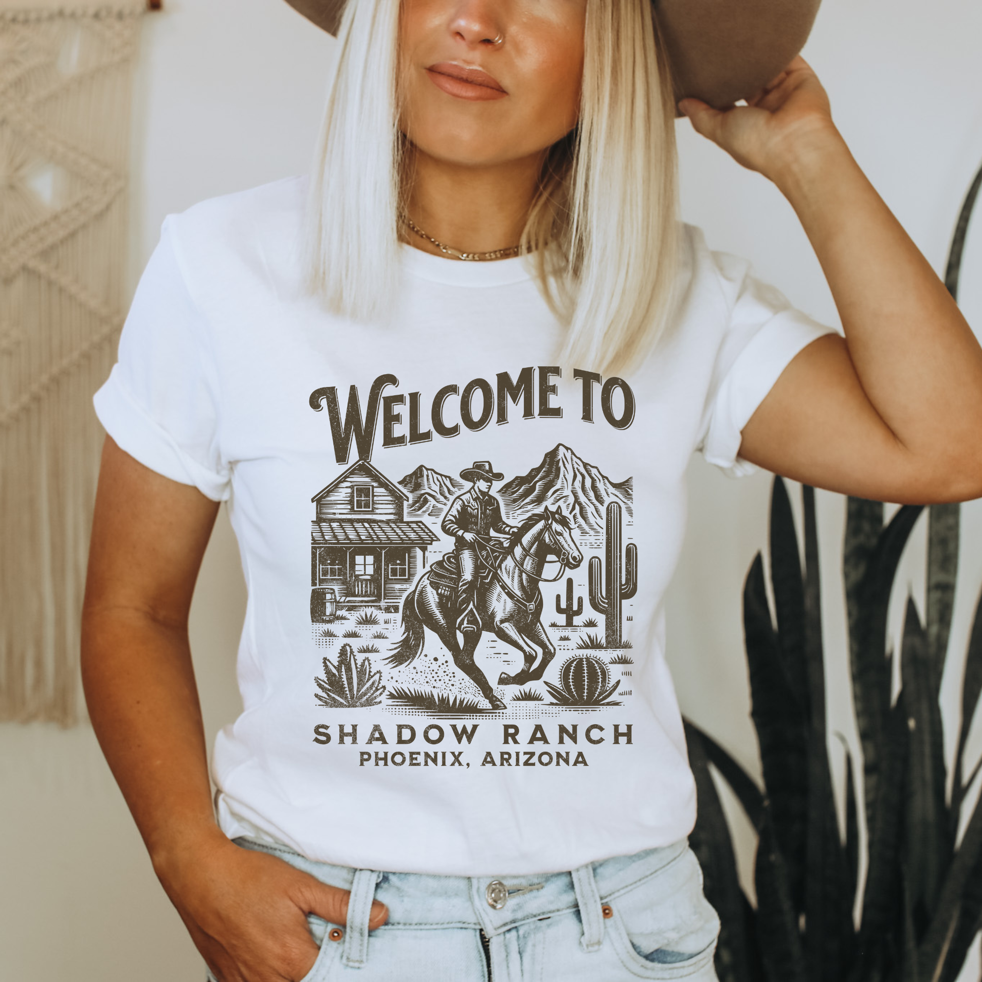 White shirt that says "Welcome to Shadow Ranch Phoenix, Arizona" with a retro graphic of a cowboy riding on a horse.