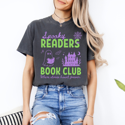  A woman wearing a Pepper Comfort colors graphic t-shirt with 'Spooky Readers Book Club' printed in green and purple, with Purple graphics including a cute ghost reading a book, a spider in its web & a haunted mansion paired with distressed blue jeans. Designed by Starlit Prose Bookish Merch Australia
