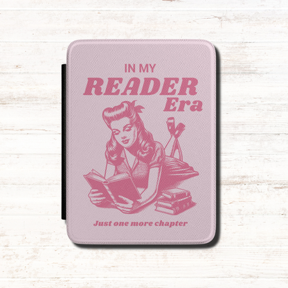 This playful pink Bookish In my Reader Era Kindle case features a vintage pin-up-inspired reader lounging with her book, paired with the phrases "In My Reader Era" and "Just One More Chapter." Pink background. Designed by Starlit Prose Bookish Merch Australia.