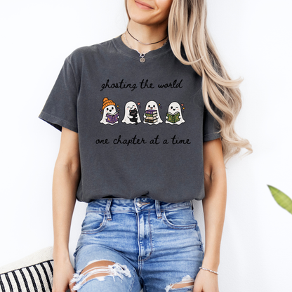 A woman wearing an oversized Pepper Comfort Colors T-shirt with four cartoon ghosts reading books and the text 'ghosting the world one chapter at a time". Designed by Starlit Prose Bookish Merch Australia