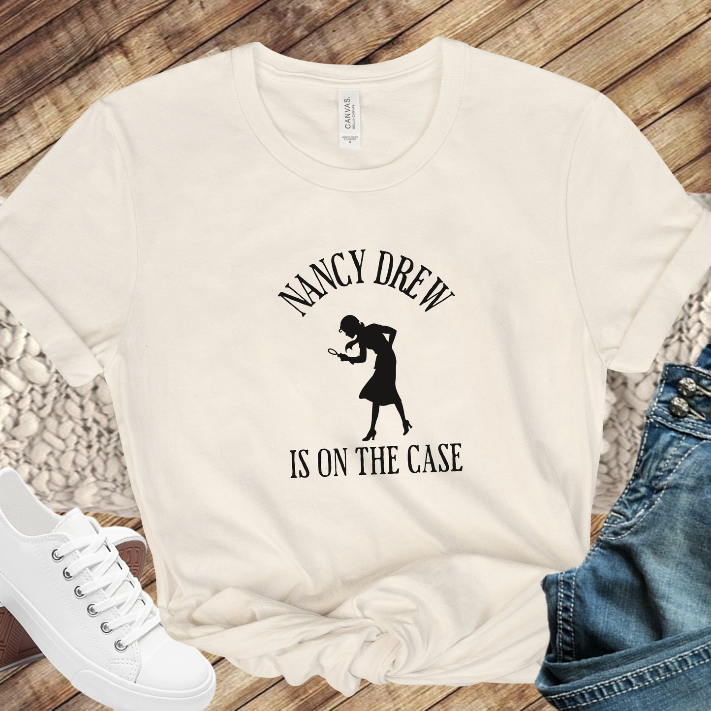 beige Shirt that says "Nancy Drew is on the Case" with a sihouette of Nancy Drew