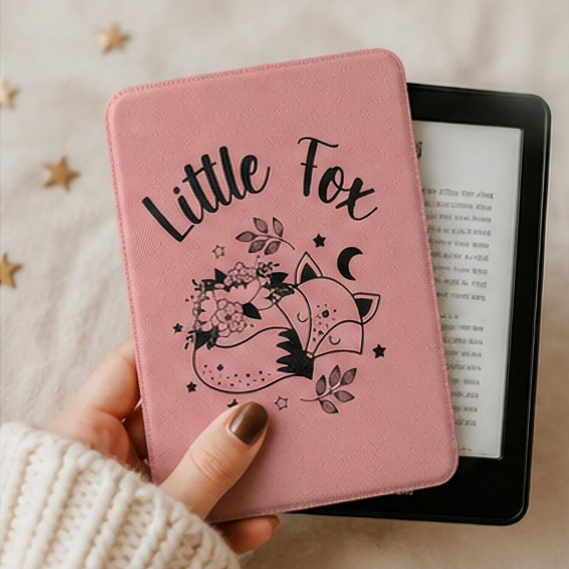 A Woman holding the pink textured Kindle Case Cover- Once Upon a Broken Heart design featuring a black line art illustration of a little fox, flowers, stars, and the words 'Little Fox'. Designed by Starlit Prose Bookish Merch Australia.