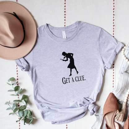 Gray t-shirt with a graphic and text 'GET A CLUE.' on a light background with decorative elements.