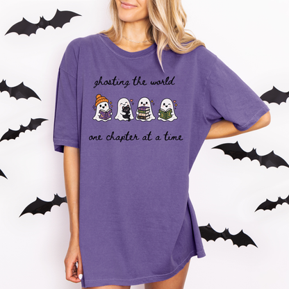 A woman wearing an oversized Grape Comfort Colors T-shirt with four cartoon ghosts reading books and the text 'ghosting the world one chapter at a time". Designed by Starlit Prose Bookish Merch Australia