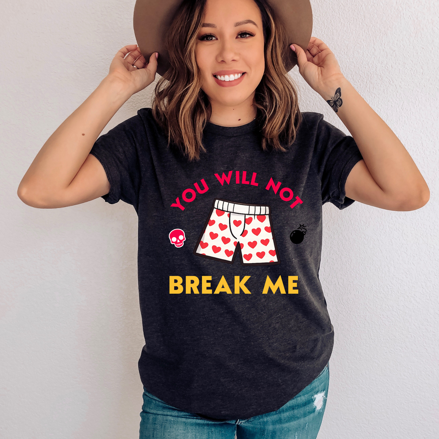 Person wearing a dark grey heather tshirt that says "You will not break me" quote from Dungeon Crawler Carl book series. Includes graphics of Carl's heart boxer shorts | Starlit Prose Bookish Merch Australia