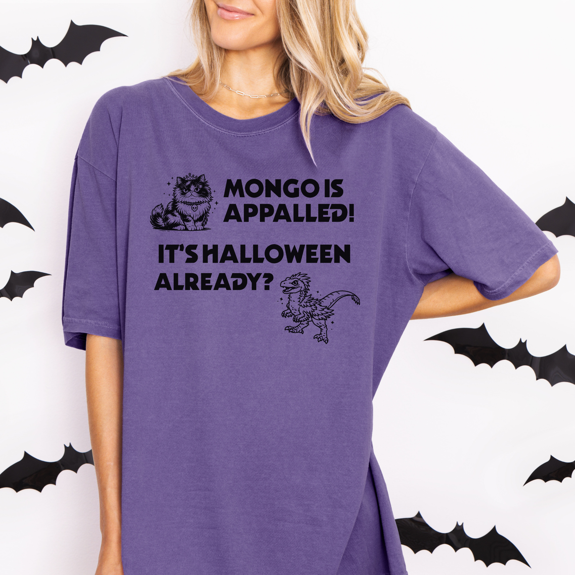 A woman wearing a Grape Purple Comfort Colors t-shirt with a Halloween design that reads 'MONGO IS APPALLED! IT'S HALLOWEEN ALREADY?' with illustrations of Princess Donut and Mongo. Designed by Starlit Prose Bookish Merch Australia