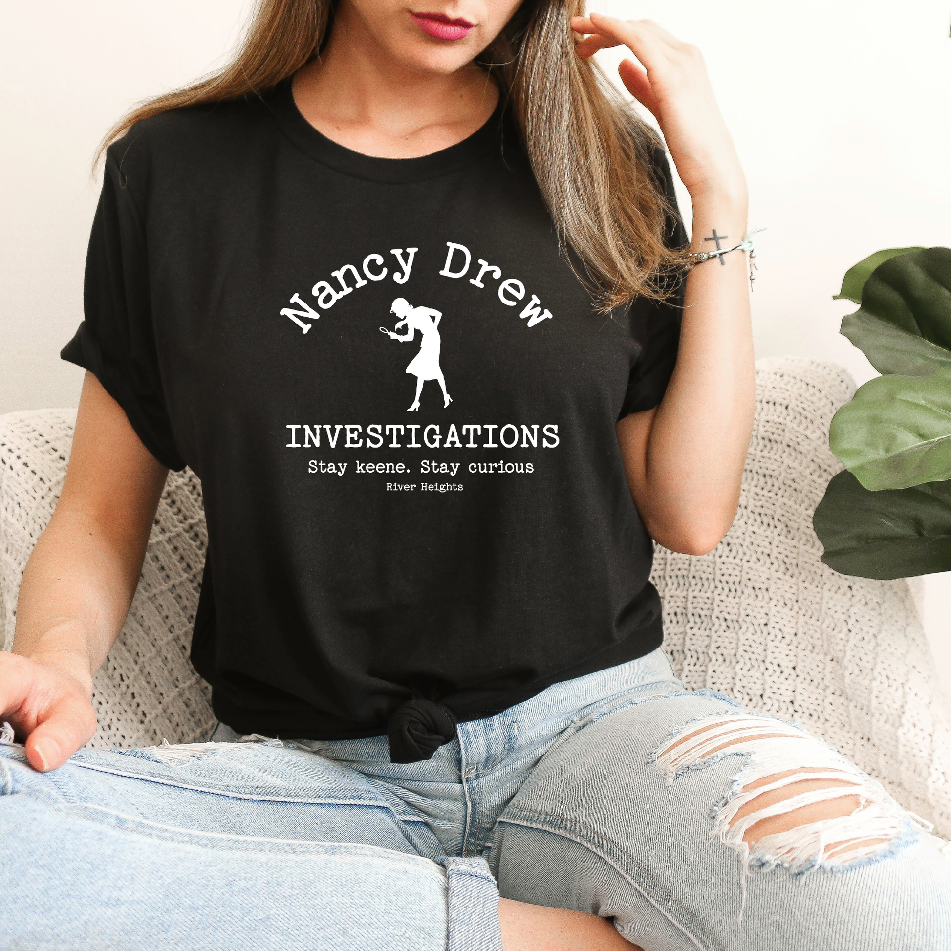 Person wearing a black t-shirt with 'Nancy Drew Investigations' design.