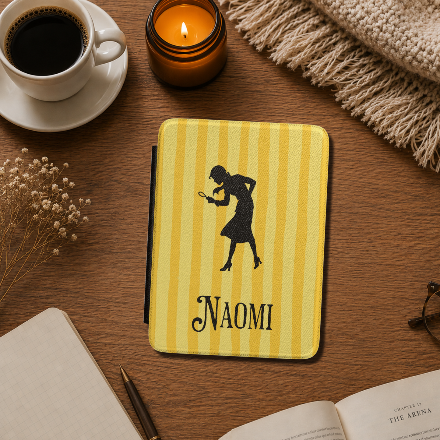 A close-up of a Personalised Nancy Drew Kindle Case, featuring a yellow vertical stripe pattern with a black silhouette of Nancy Drew holding a magnifying glass and a custom name in vintage style typography at the bottom. Designed by Starlit Prose Bookish Merch Australia.