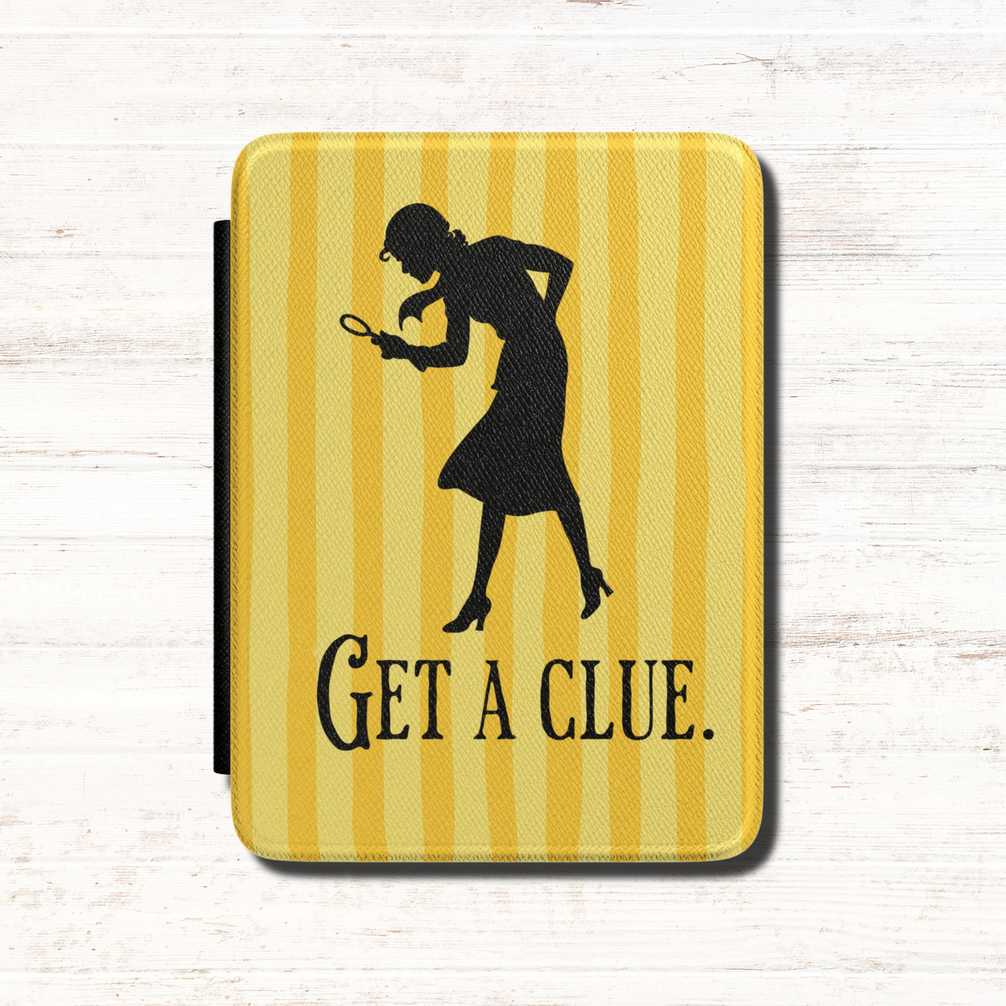 A kindle case featuring a vintage-style  Nancy Drew design with vertical yellow stripes, a black silhouette of a Nancy Drew holding a magnifying glass, and the text 'GET A CLUE.' Designed by Starlit Prose Bookish Merch Australia.