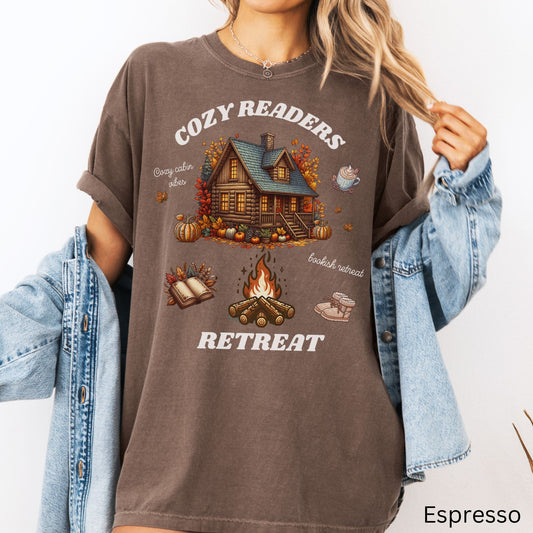 Woman wearing a Espresso Comfort Colors Tee with 'Cozy Readers Retreat' design including a cozy cabin, pumpkin spice latte, cute slippers, campfire, pumpkins and a book. Starlit Prose Bookish Merch Australia