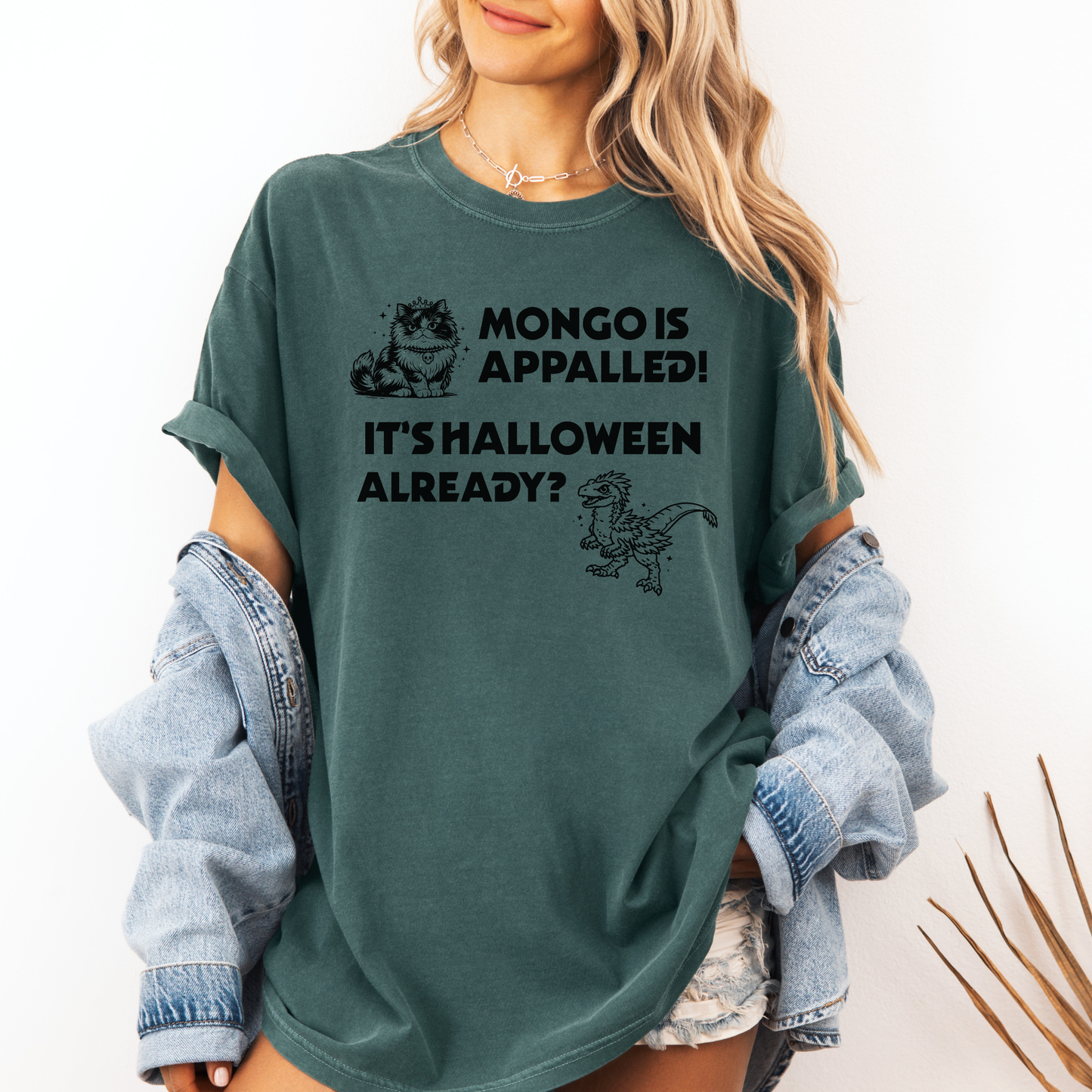 A woman wearing a Seafoam Green Comfort Colors t-shirt with a Halloween design that reads 'MONGO IS APPALLED! IT'S HALLOWEEN ALREADY?' with illustrations of Princess Donut and Mongo. Designed by Starlit Prose Bookish Merch Australia