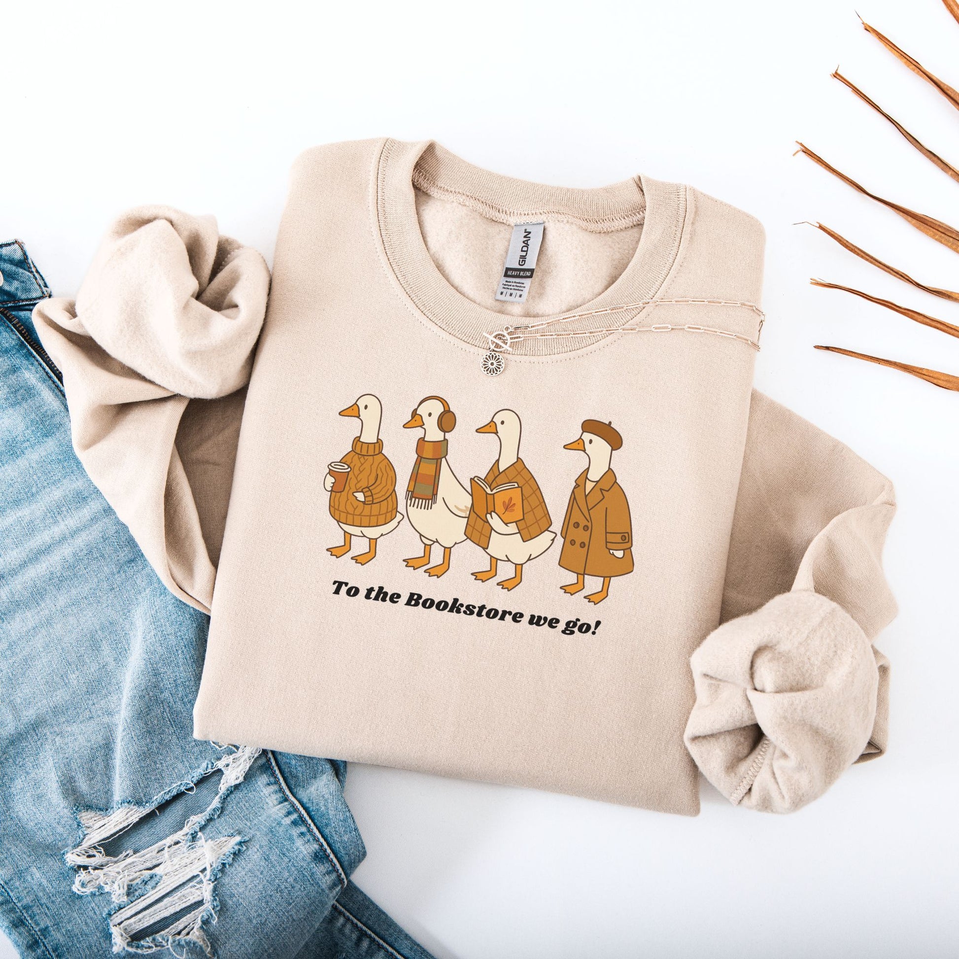 Sand sweatshirt with duck graphic and text 'To the Bookstore we go!' on a white background. Starlit Prose Bookish Merch Australia