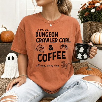 A woman wearing an oversized Yam Orange graphic Comfort colors T-shirt with black text reading 'give me DUNGEON CRAWLER CARL & COFFEE all day, every day' and small illustrations - including Carl's pajama shorts, Princess Donut & Mongo. Designed by Starlit Prose, Bookish Merch Australia