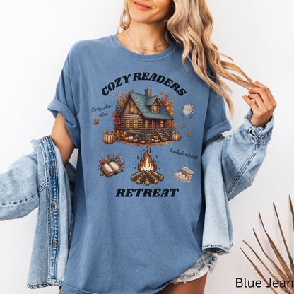 Woman wearing a Blue Jean Comfort Colors Tee with 'Cozy Readers Retreat' design including a cozy cabin, pumpkin spice latte, cute slippers, campfire, pumpkins and a book. Starlit Prose Bookish Merch Australia
