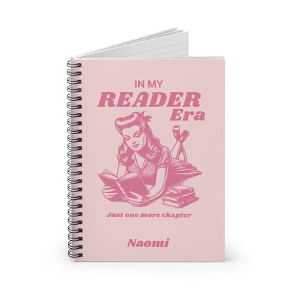 This cute bookish personalised spiral notebook features a soft light pink background, a vintage-inspired pin-up girl reading a book and the phrases "In My Reader Era" and "Just One More Chapter." A personalised section allows you to add the recipient's name, turning an already bookish design into a thoughtful gift made especially for them. Designed by Starlit Prose Bookish Merch Australia.
