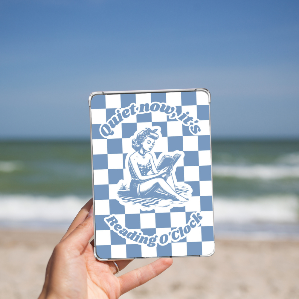 Woman holding the blue Retro Summer Beach reading Kindle insert while on a beach. 
