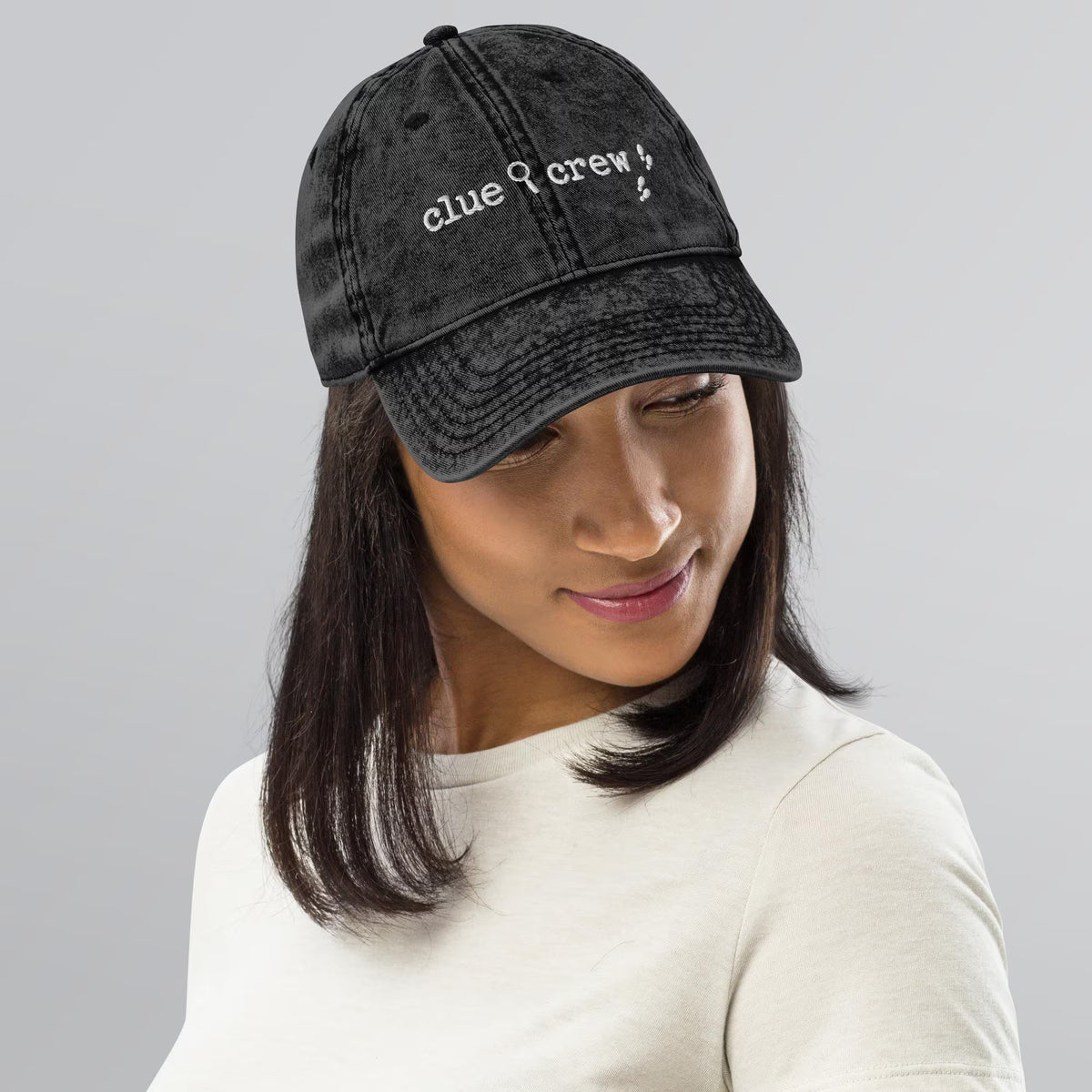 A Nancy Drew vintage distressed style embroidered Dad hat features “Clue Crew” alongside a magnifying glass and tiny footsteps. Designed by Starlit Prose Bookish Merch Australia.