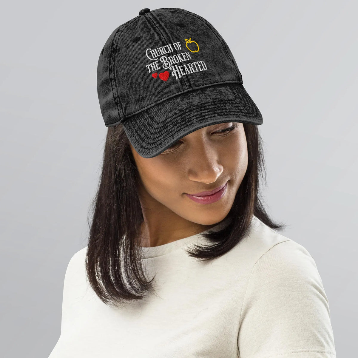 Once Upon a Broken Heart embroidered hat , distressed Vintage style hat features text that says “Church of the Broken Hearted”, with a delicate gold apple outline, and tiny red hearts. Designed by Starlit Prose Bookish Merch Australia.