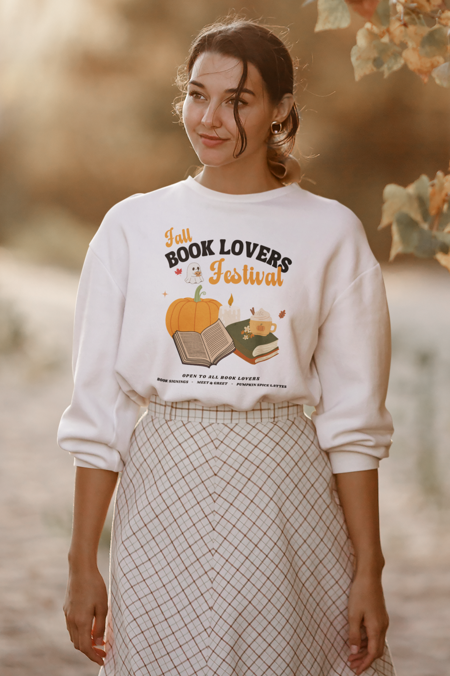 Woman wearing a White sweatshirt with 'Fall Book Lovers Festival' design featuring a pumpkin, books, and a ghost for a fictional Book Lovers Festival. Starlit Prose Bookish Merch Australia
