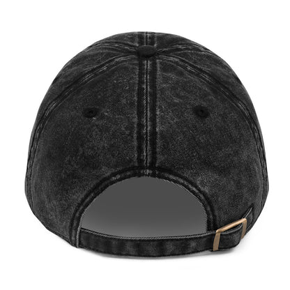 The back view of a black acid-wash baseball cap with a dark gray adjustable strap and a small gold-tone metal buckle.