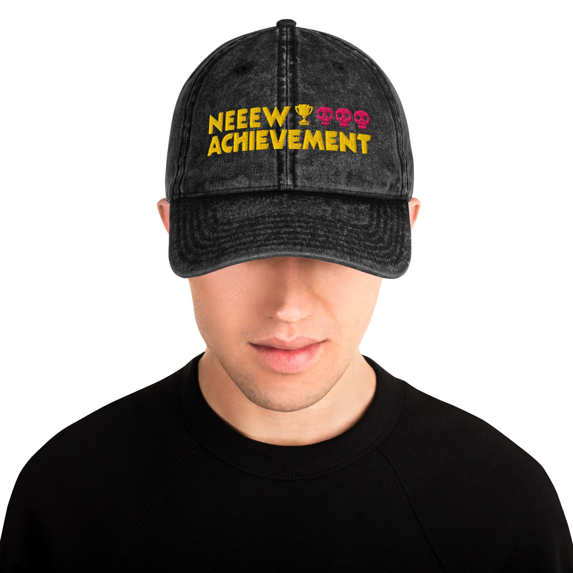 A man wearing a Dungeon Crawler Carl baseball cap with yellow and pink embroidered text reading 'NEEW ACHIEVEMENT' on a white background. Starlit Prose Bookish Merch Australia