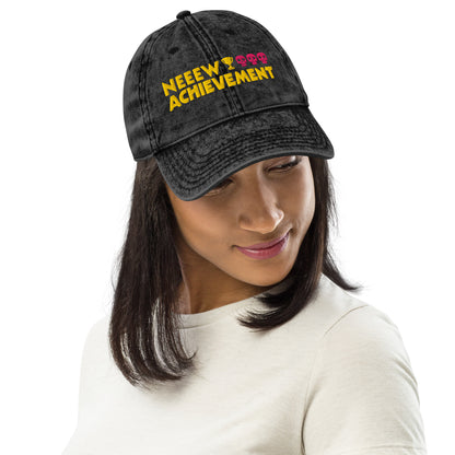 A woman wearing a black washed Dungeon Crawler Carl baseball cap with yellow and pink embroidered text reading 'NEEW ACHIEVEMENT' on a white background. Starlit Prose Bookish Merch Australia