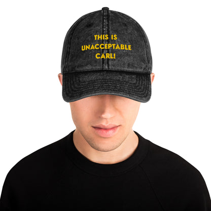 A man wearing a washed black denim baseball cap that says "This is unacceptable Carl" in yellow embroidered text. Quote from Princess Donut of Dungeon Crawler Carl book series. Designed by Starlit Prose Bookish Merch Australia