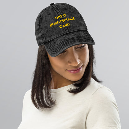 Woman wearing a black washed cap that says "This is unacceptable Carl" in yellow embroidered text. Quote from Princess Donut of Dungeon Crawler Carl book series. Designed by Starlit Prose Bookish Merch Australia