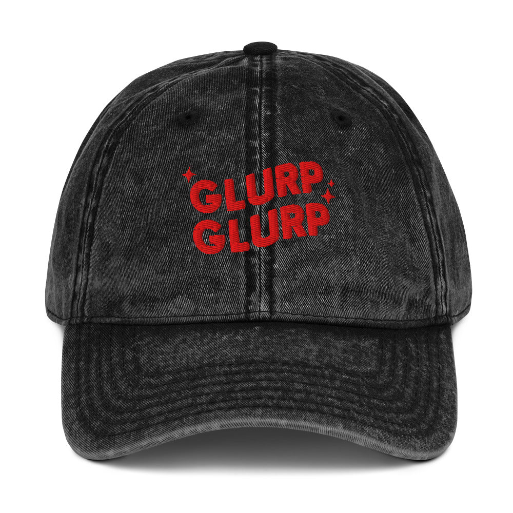 A black acid-wash baseball cap with 'GLURP GLURP' embroidered in red on the front, a quote from Dungeon Crawler Carl book series, shown against a plain white background. Designed by Starlit Prose Bookish Merch Australia