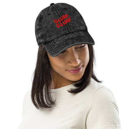 A woman wearing A black acid-wash baseball cap with 'GLURP GLURP' embroidered in red on the front, a quote from Dungeon Crawler Carl book series, shown against a plain white background. Designed by Starlit Prose Bookish Merch Australia