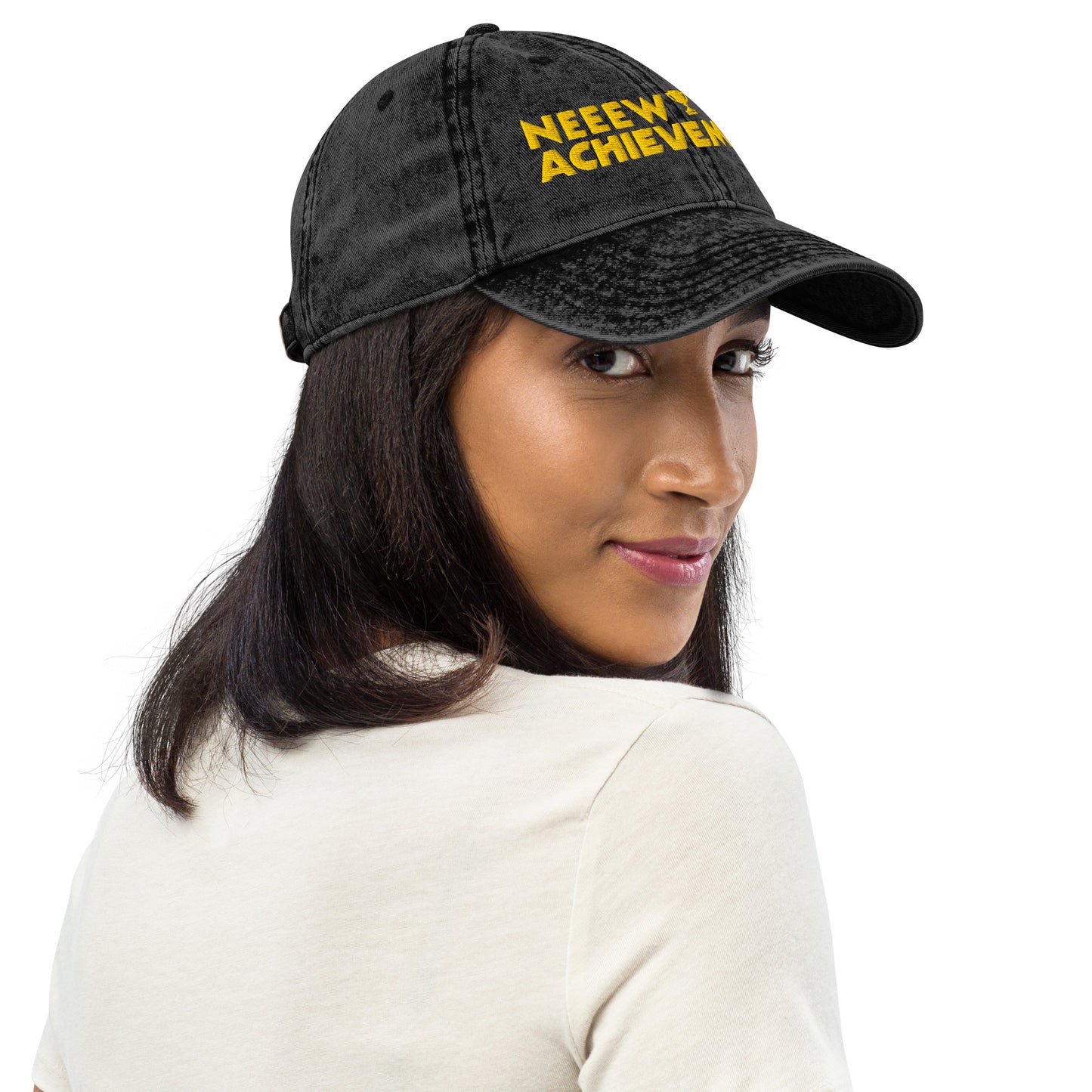 A woman wearing a black washed baseball cap Dungeon Crawler Carl baseball cap with yellow and pink embroidered text reading 'NEEW ACHIEVEMENT' on a white background. Starlit Prose Bookish Merch Australia