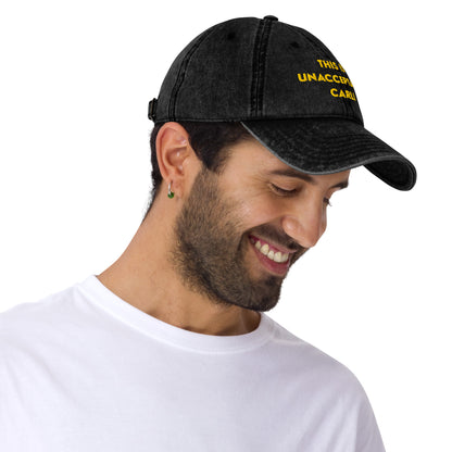 Side view of a Man wearing A washed black denim baseball cap that says "This is unacceptable Carl" in yellow embroidered text. Quote from Princess Donut of Dungeon Crawler Carl book series. Designed by Starlit Prose Bookish Merch Australia