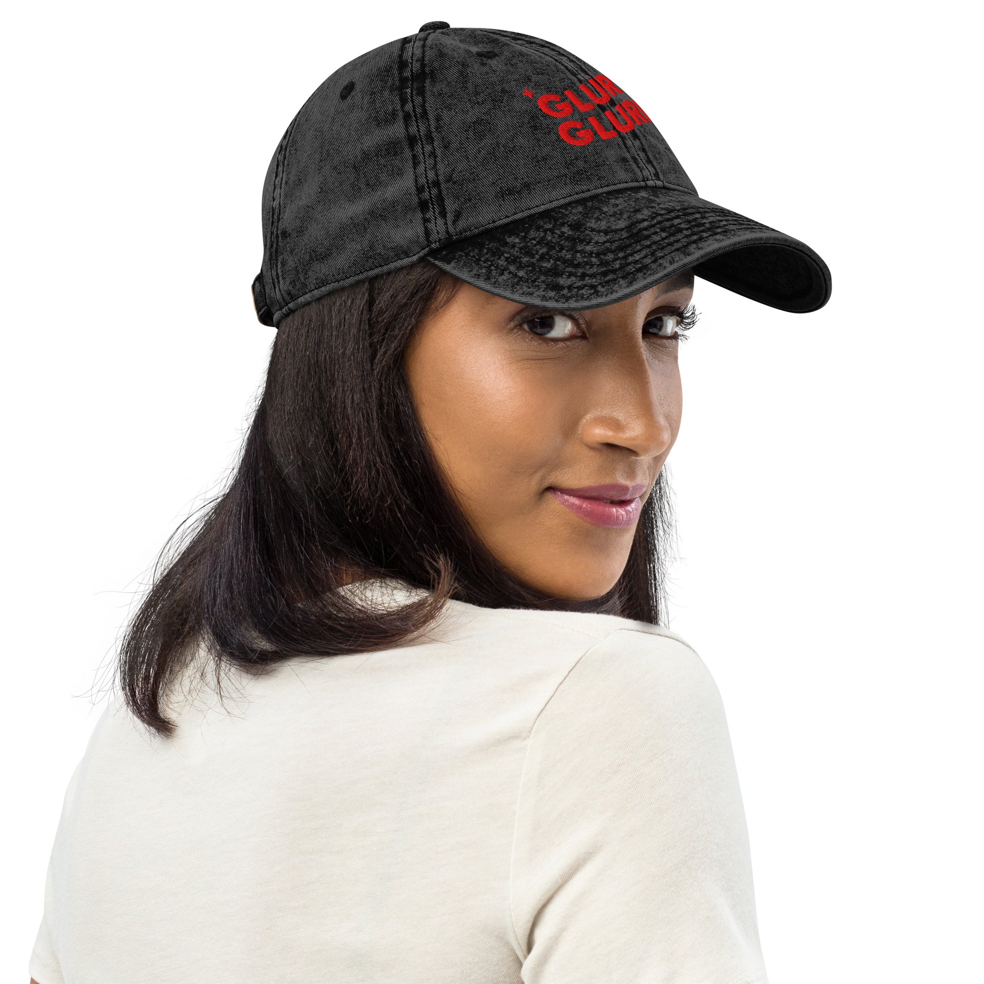 Side view of a Woman wearing A black acid-wash baseball cap with 'GLURP GLURP' embroidered in red on the front, a quote from Dungeon Crawler Carl book series, shown against a plain white background. Designed by Starlit Prose Bookish Merch Australia